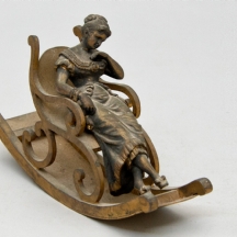 פסל ברונזה עתיק בדמות אישה על כיסא נדנדה