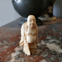 פסלון שנהב סיני בדמות בודהה שסובל מגלי חום ואוחז במניפה