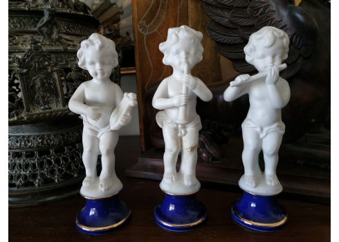 סט של שלושה פסלוני ילדים מנגנים, עשויים ביסקוויט לבן ובסיסי פורצלן מעוטרים זהב