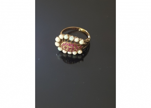 טבעת עתיקה עשויה זהב משובצת במרכזה כיפת אבני רובי אדומות ובהיקף בצורת פרסת סוס
