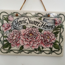 שלט חרסינה לתליה על הקיר מעוטר בכיתוב: 'Home, sweet home'