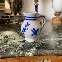 קנקן גרמני קטן עשוי חרס, מעוטר בזיגוג מלח (Salt-glaze) וסמל בדמות נשר, חתום