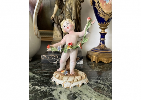 פסלון ישן בסגנון עתיק, עשוי חרס בדמות מלאך וגרלנדת פרחים, מעוטר בצביעת יד