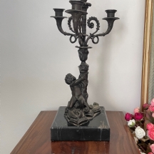 קנדלברה ישנה בסגנון עתיק, עשויה בסיס שיש שחור מנומר וגוף ברונזה מפוסל בדמות ילד