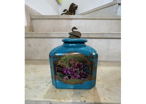 קופסא ומכסה תואם עשויים חרס ומתכת מפוסלת בדמות ברבור, מעוטר בהדפס של שושנים