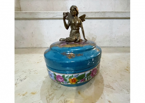 קופסא עגולה ומכסה תואם עשויים חרס ומתכת מפוסלת בדמות פיה צעירה, מעוטרת