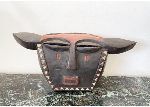 מסכת עץ אפריקאית עתיקה בדמות ראש חיה עם אוזניים לצדדים, עיטור צבעוני של משולשים