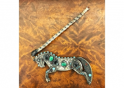 קישוט טורקמני בדמות סוס ושוט, עשוי מתכת מצופה כסף ופליז, משובץ אבנים צבעוניות