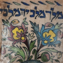 אריח קרמיקה פרסי דקורטיבי מעוטר בכיתוב עברי: 'מלך מלכי המלכים'