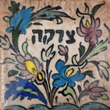 אריח קרמיקה פרסי דקורטיבי מעואריח קרמיקה פרסי דקורטיבי מעוטר בכיתוב עברי: 'צדקה'