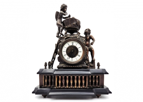 שעון קמין ישן בסגנון צרפתי עתיק, עשוי מתכת ובסיס מצפחה שחורה, מעוטר בדמות ילדים