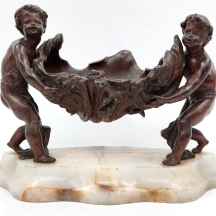 סנטרפיס צרפתי עתיק מתקופת סגנון ה'בל אפוק' בדמות שני ילדים נושאים צדף גדול