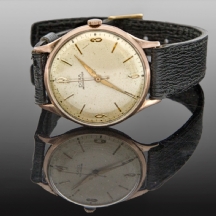 שעון יד ישן לגבר מתוצרת חברת DOXA עשוי זהב אדום רצועה עור שחור.