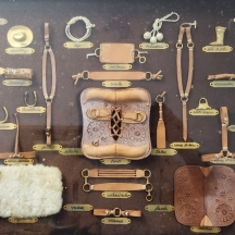 מסגרת ובה דגמים מוקטנים ממתכת ועור המדגימים את תרבות חיי הכפר הדרום אמריקאית