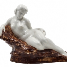 פסל קרמיקה בן כמאה שנה מהשליש הראשון של המאה העשרים, בדמות ערום נשי שרועה על סלע