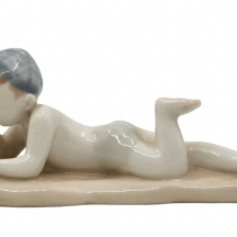 פסלון פורצלן רוסי ישן מתוצרת 'לומונוסוב' (Lomonosov), בדמות ילד שוכב על בטנו