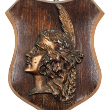 פלק דקורטיבי לתלייה על הקיר מעוטר בתבליט בדמות ראש אישה אינדיאנית עשוי נחושת