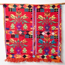 טקסטיל מסורתי עם עיטורים גיאומטריים צבעוניים על רקע אדום