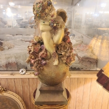 פסל בדמות מלאך ישן על כדור עשוי חומר יצוק ופרחי בד