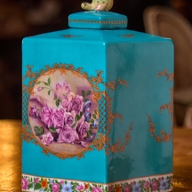 מיכל חרסינה ומכסה תואם מעוטר בהדפס שושנים על רקע בגוון טורקיז, חתום