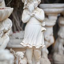 פסל גינה בדמות ילדה מחזיקה אפרוח לצד תרנגולת