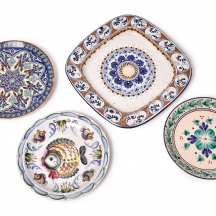 ארבע צלחות הגשה וכיבוד עשויות חרס מעוטרות בעבודת יד, חלקן חתומות