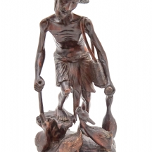 פסל עץ מגולף ביד המתאר דייג בעבודתו, עם פרטי גילוף עשירים ודמויות עופות בבסיס