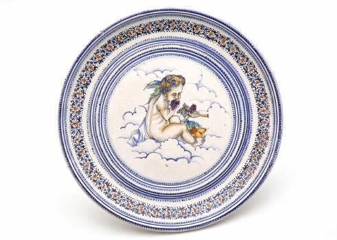 צלחת דקורטיבית עשויה מיוליקה, מעוטרת ציור יד של דמות 'Putto' קלאסית חתומה