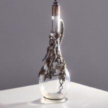 דקנטר קריסטל מעוטר במסגרת מתכת מצופה כסף בעבודת תבליט עשירה, בדמות אישה